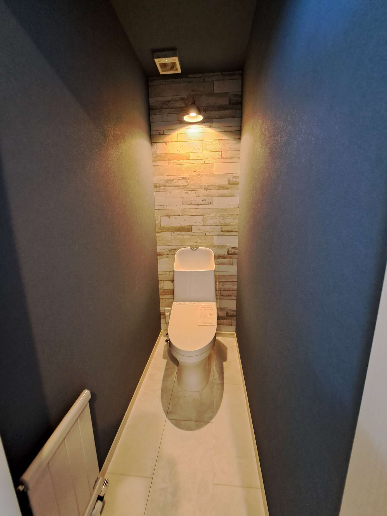 トイレ - 壁からの照明とアクセントのクロスを使ったちょっとお洒落な雰囲気のあるトイレ。 -  - 